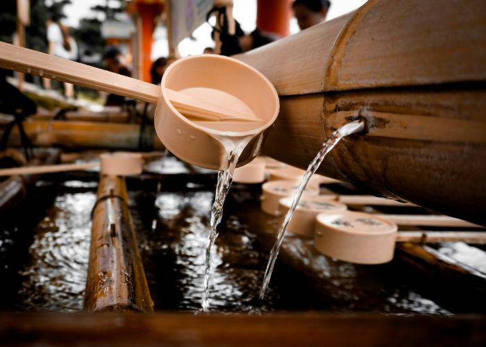 Water pouring from a bamboo pipe with small bamboo ladles to purify your hands upon entering a Japanese shrine